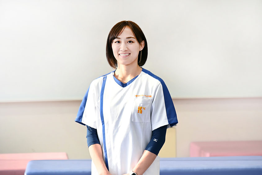 小倉リハビリテーション学院の実習室で白衣を着て笑顔で立つ理学療法学科の在校生Pさん